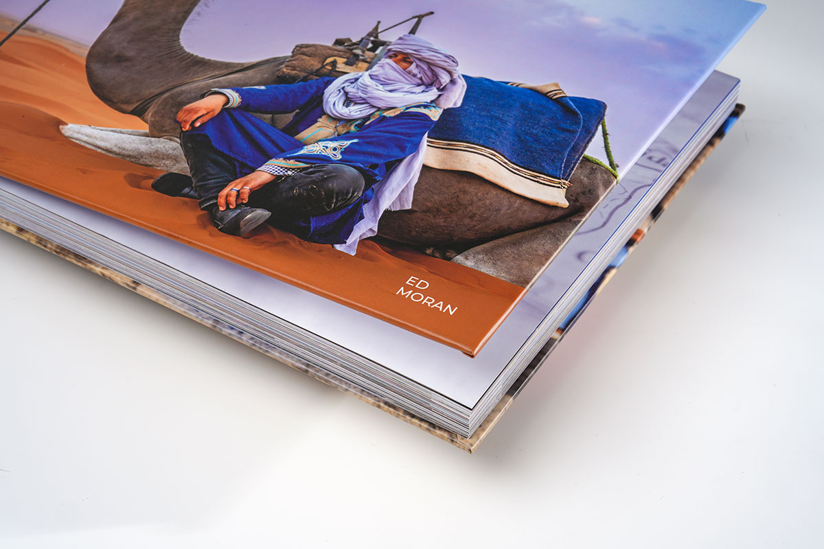Lifted cover of a travel photography coffee table book revealing 3.5mm thick cover board and high-quality matte finish