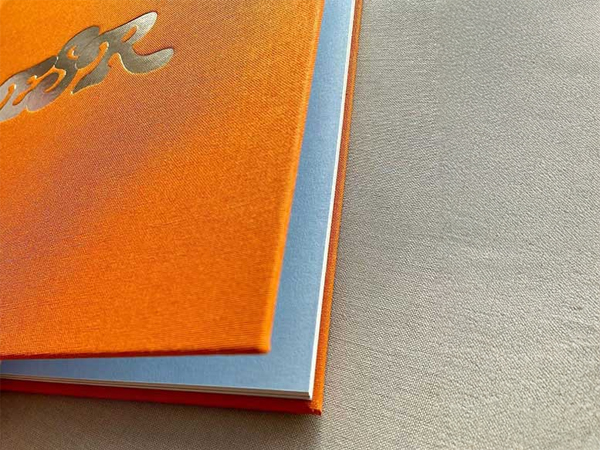 Orange cloth hardcover book with a blue endsheet and silver cover detail