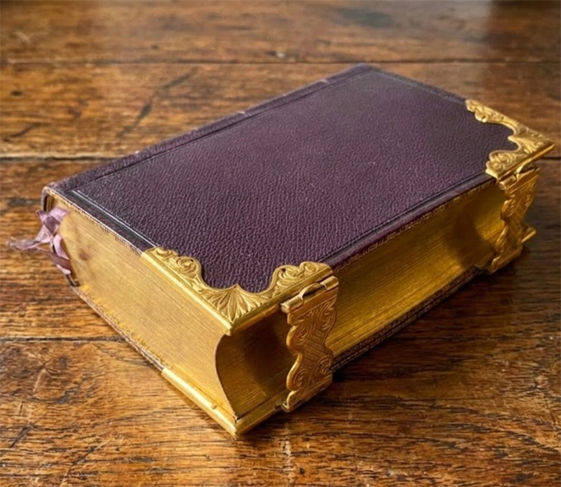 Close-up of a vintage leather-bound Book of Common Prayer with gold-gilded page edges.