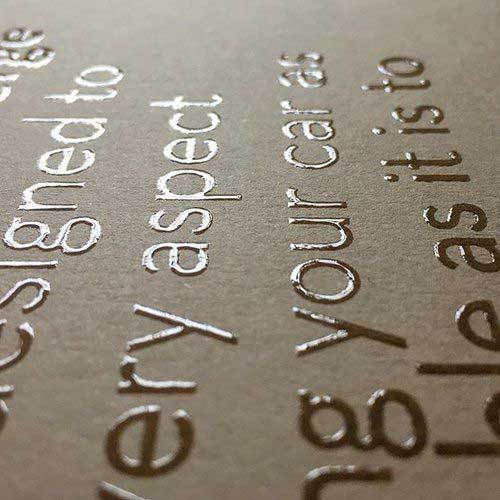 Close-up of raised UV lettering with glossy, embossed text on a matte background.