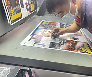 Press operator inspecting an offset printed sheet