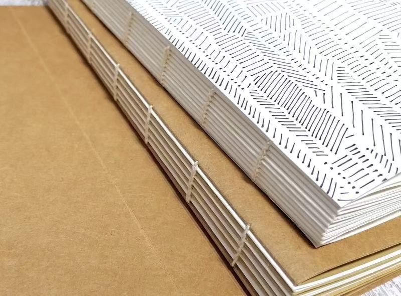 Freshly sewn book block — the folded page groups (signatures) have just been stitched together with thread, forming the book block before trimming and casing in.