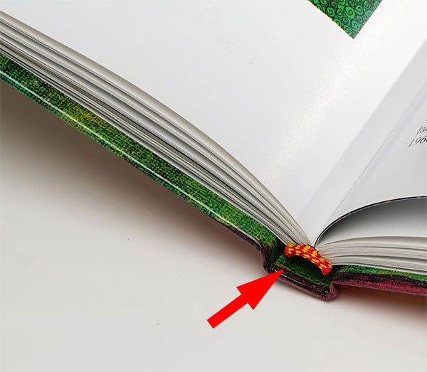 A red arrow pointing to a yellow and red striped tailband in an art book